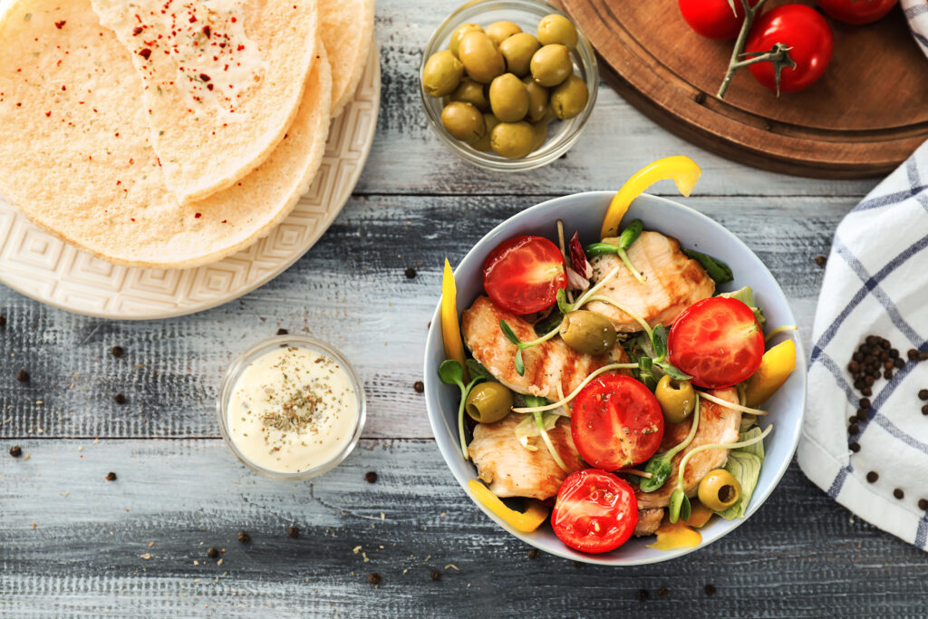 Ahşap masada tavuk, salata, soslu kase